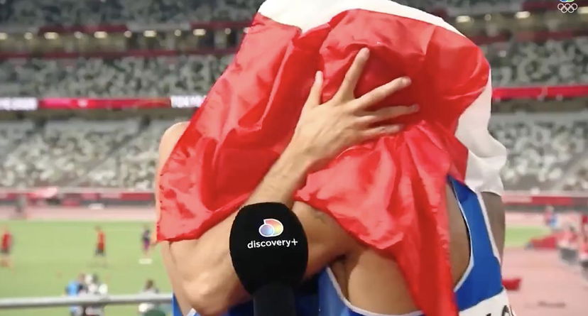 Marcell Jacobs e Gianmarco Tamberi si baciano sotto la bandiera italiana per festeggiare la medaglia d’oro preview