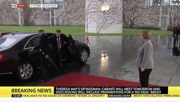 Theresa May è bloccata nella sua auto, mentre Angela Merkel la aspetta fuori
