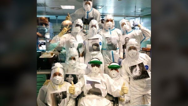L’immagine degli infermieri della terapia intensiva con una foto del viso sorridente attaccata al petto