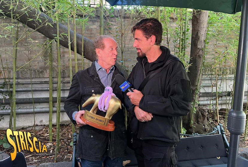 Memo Remigi riceve il Tapiro da Striscia la Notizia, ecco come ha risposto a Valerio Staffelli che gli ha chiesto: “Che gioco è toccare il cul* a una persona?” preview