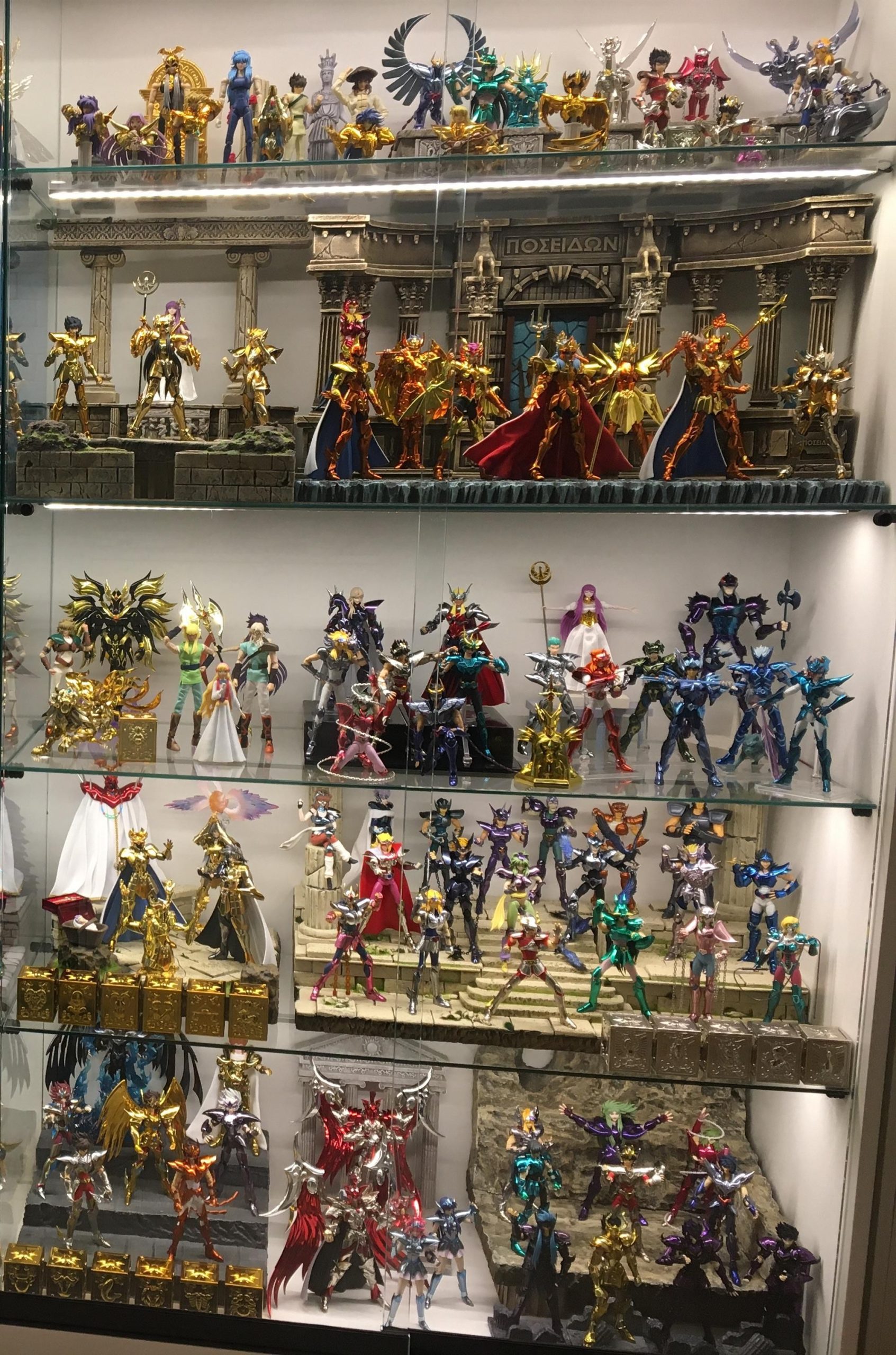 Collezione di figure Saint Seiya Myth Cloth esposte in una vetrina su più ripiani