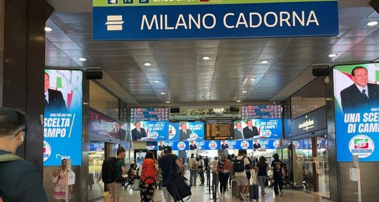 È il 2022 ma sembra il 1994: lo straniante viaggio nel tempo con Berlusconi giovane alla stazione Cadorna a Milano | VIDEO